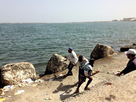 Several men tugging on a large fishing net submerged in the sea, Alexandria.