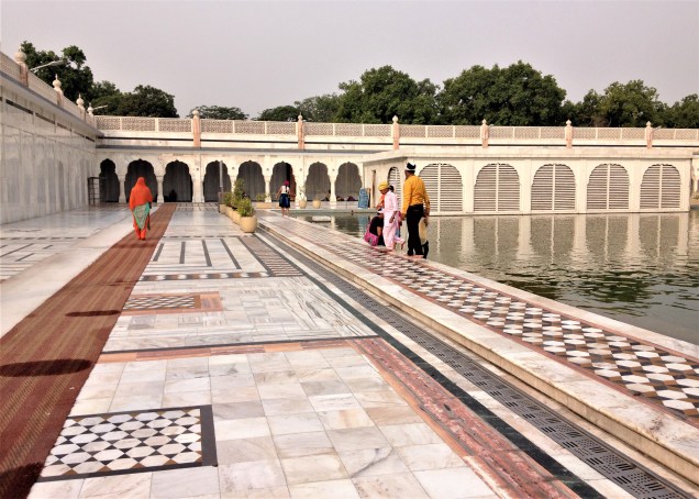 A corner of the holy pond at Gurudwara Bangla Sahib, New Delhi, with family group. Photo shows marble surround with inlaid decorations.