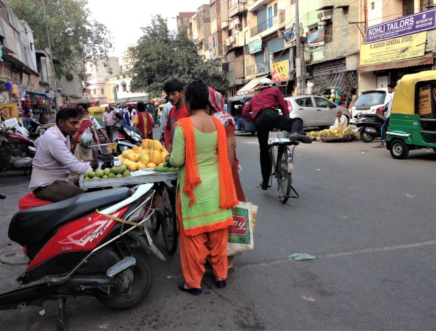 A street shot in Pahar Ganj, Delhi, showing a lady buying mangos from a street vendor.