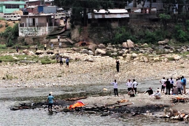 Confluence of Saryu and Gomti rivers, and men carrying wood down to the burning site for the day's funeral fires. Bhagnath Temple, Bageshwar, Uttarakhand.