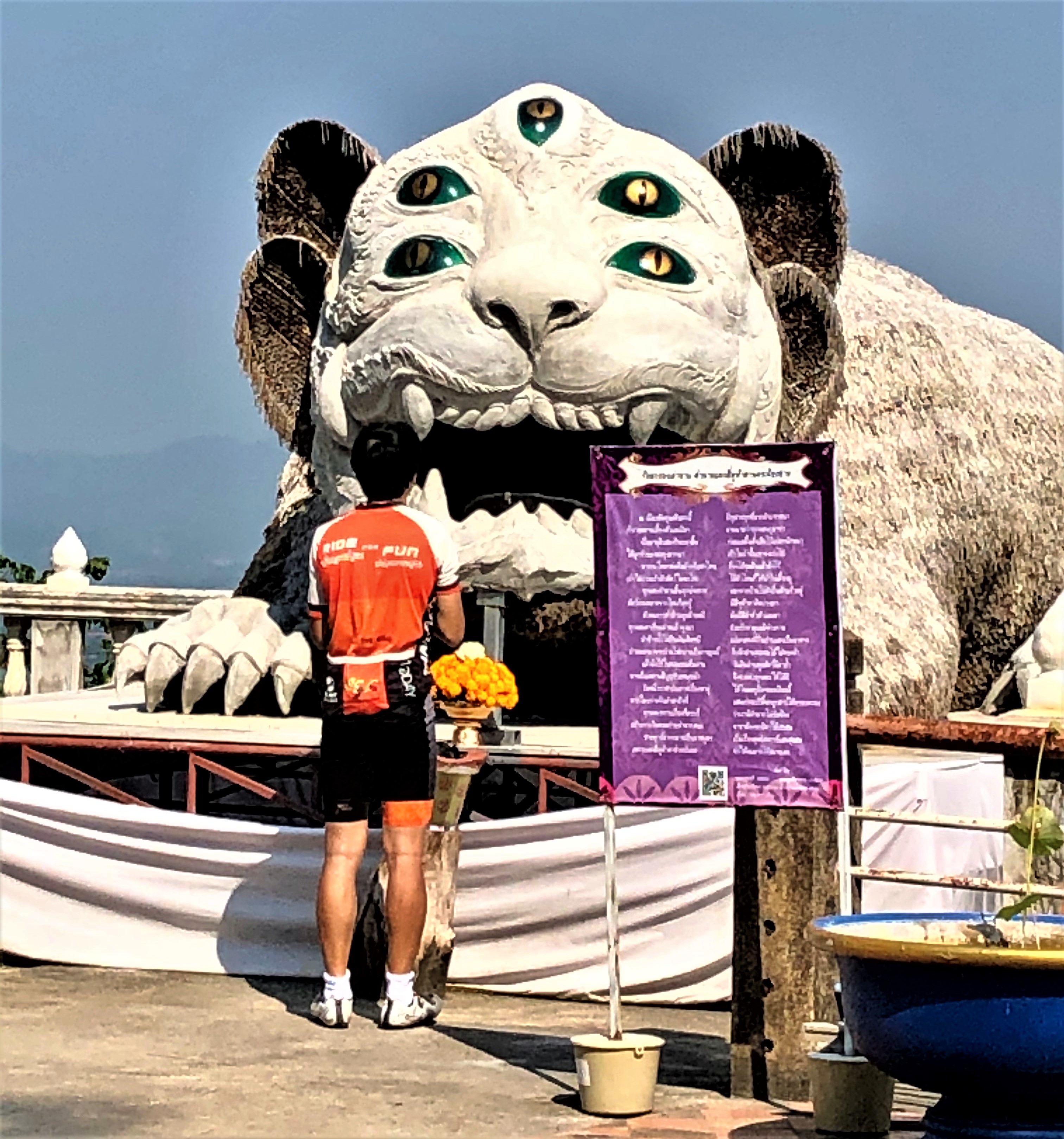 Cyclist making his offering to the large Sihuhata at Wat Phra That Doi Khao Kwai