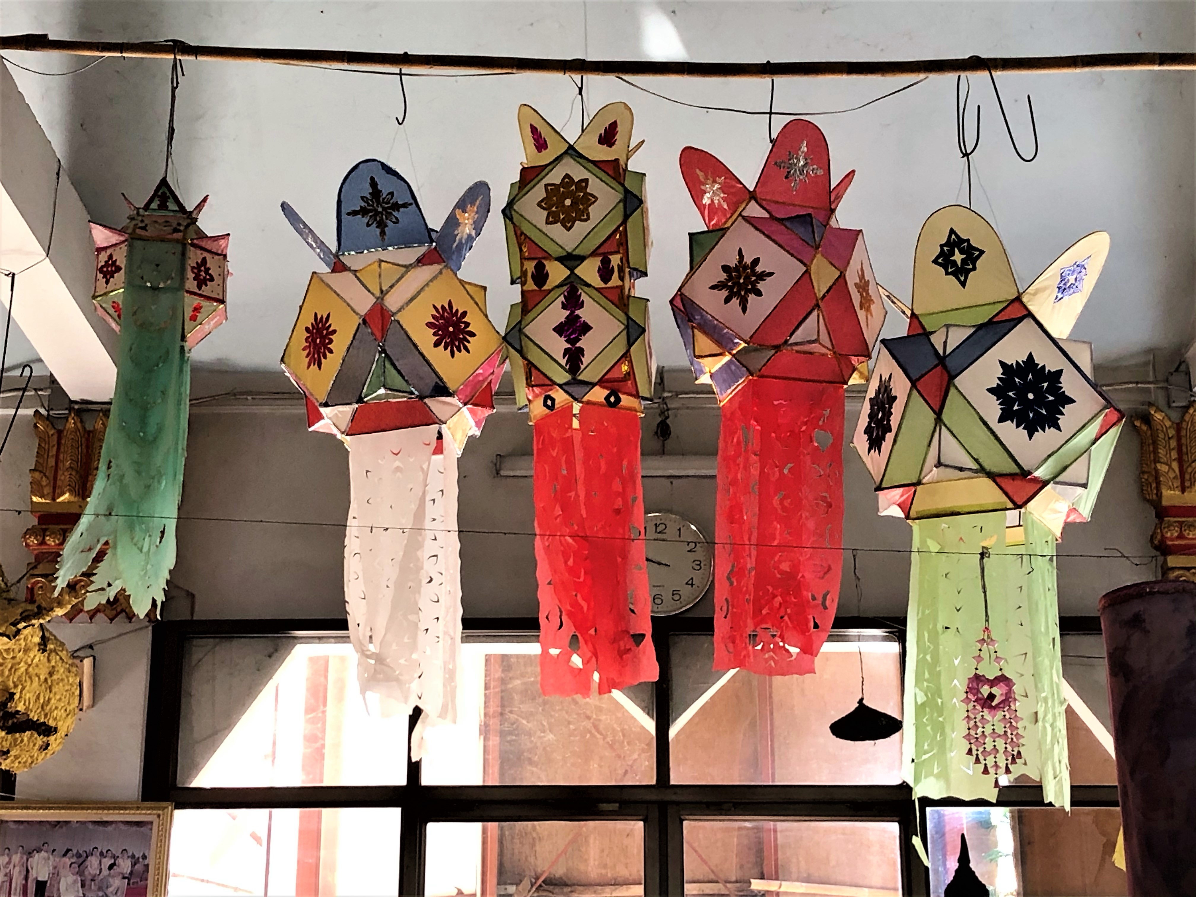 A row of colorful paper lanterns hanging from the ceiling in the main temple.