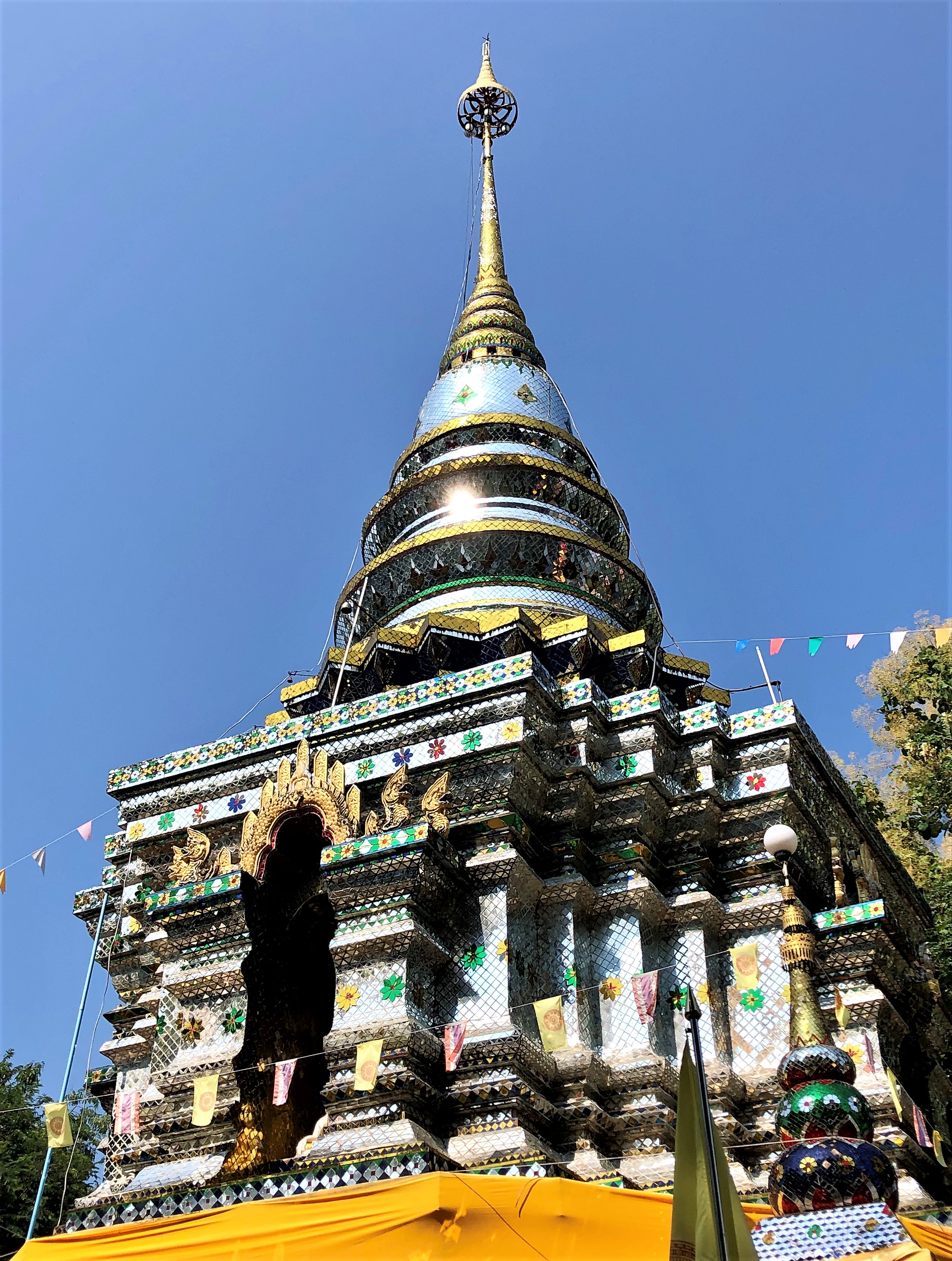 The stupa at Wat Phra That Doi Khao Kwai is completely covered in mosaic patterns of mirrored tiles.