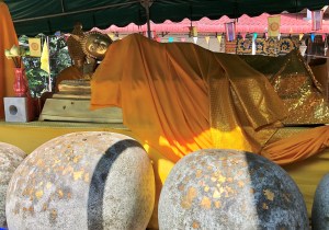 Image of reclining Buddha with round boulders in front, ornamented with gold leaf.